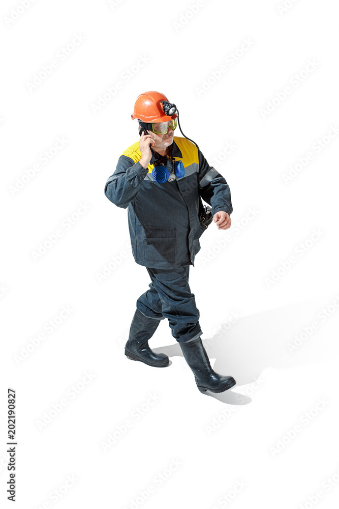 The studio shot of senior bearded male miner standing at the camera on a white background. The studio shot of senior bearded male miner standing at the camera on a white background.