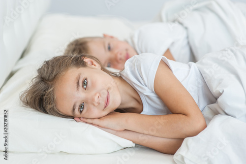 Happy girl with brother lying on bed