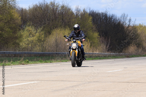 Male motorcyclist at the wheel of a racing motorcycle on a high-speed empty road. with pleasure passing an empty road to travel by motorcycle. Place for text, extreme sport, freedom concept