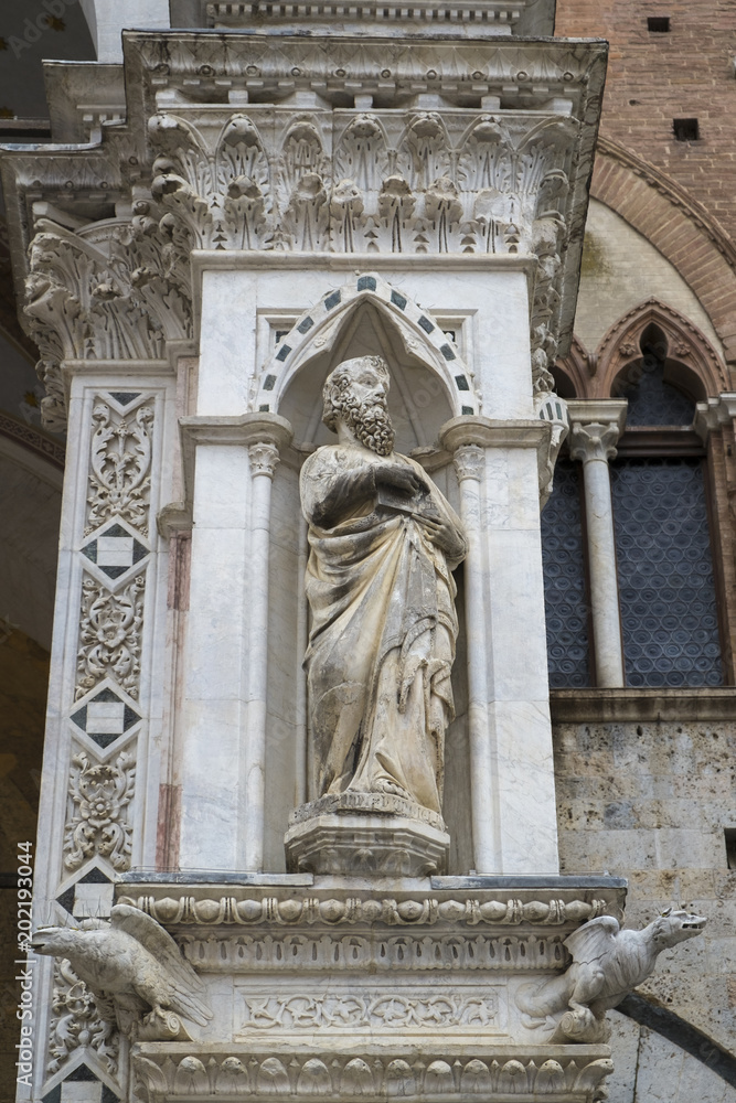 Statue on the column of Torre Del Mangia on Central city square called Piazza Del Campo in Siena, Italy