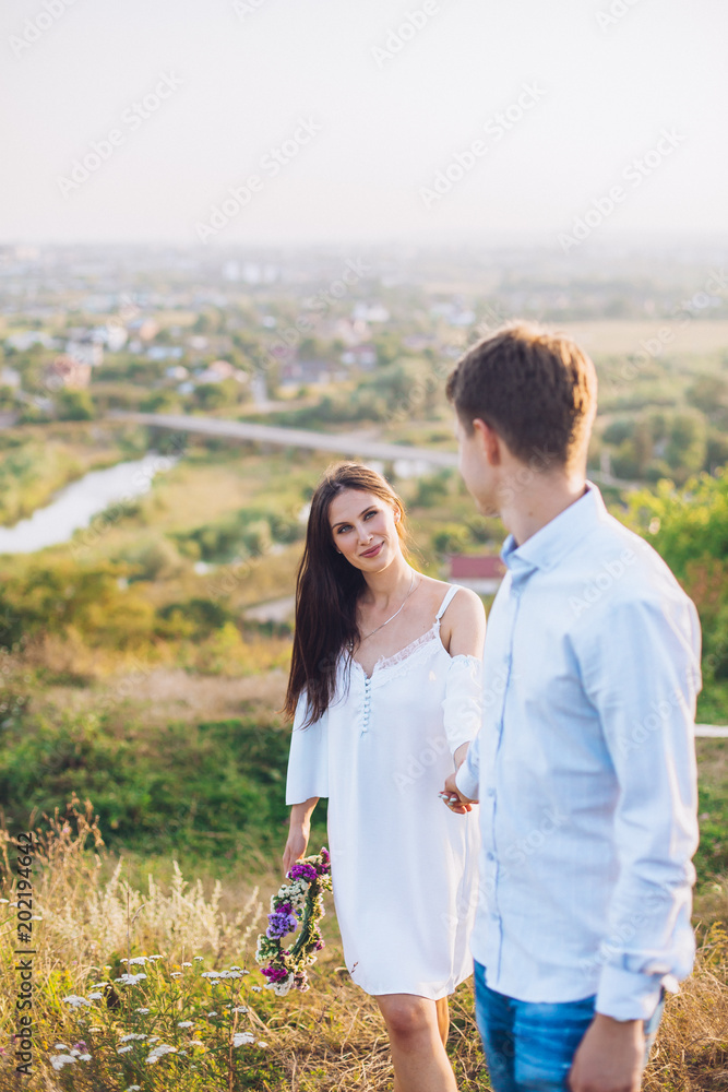 couple standing on the hill hugging and looking on city view from the top of the hill. Young couple in love. Sunny day. couple standing on the hill hugging and looking on city view from the top of the hill. Young couple in love. Sunny day.