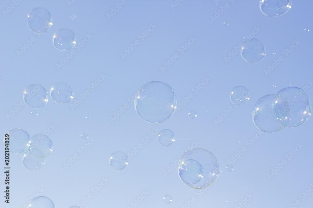 Many large soap bubbles flying in blue sky