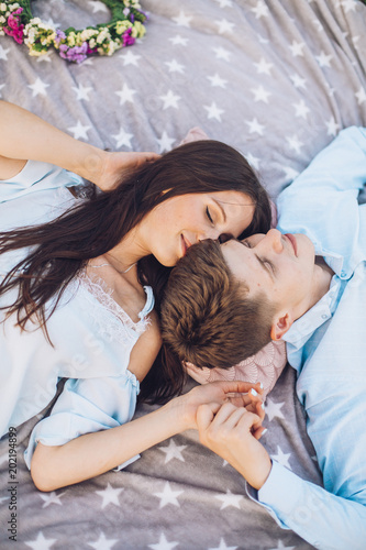 top view of a couple in love lying on a picnic plaid. Man and woman having rest outdoor picnic. Young couple hug each other.