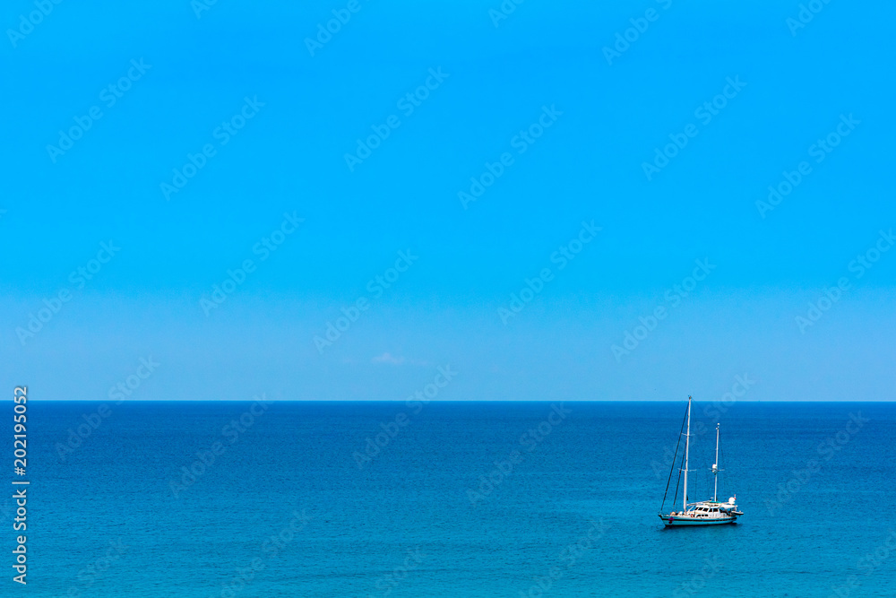 Blue sea with sailboat sailing the ocean.