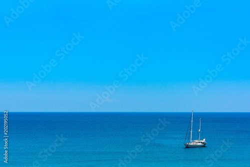 Blue sea with sailboat sailing the ocean.