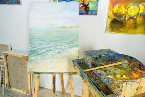 canvas on easel and paintings on wall in workshop © LIGHTFIELD STUDIOS