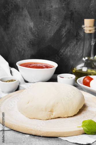 Pizza dough and ingredients for pizza on gray background