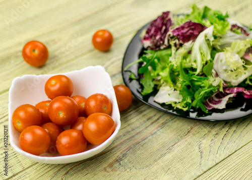 Vegetarian salad of fresh vegetables and tomatoes cherry plate on a wooden background.