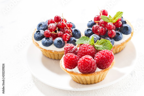 mini tarts with cream and fresh berries on white background