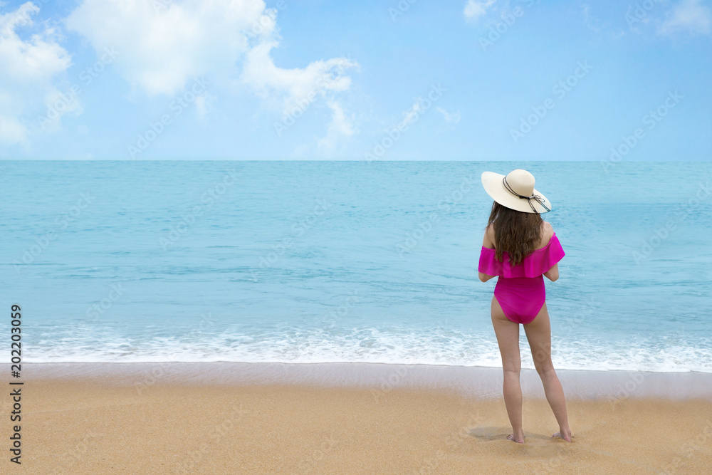 Beautiful woman in pink bikini and straw hat on the sea shore , Relaxed and enjoying tropical beach and summer vacation Beautiful woman in pink bikini and straw hat on the sea shore , Relaxed and enjoying tropical beach and summer vacation