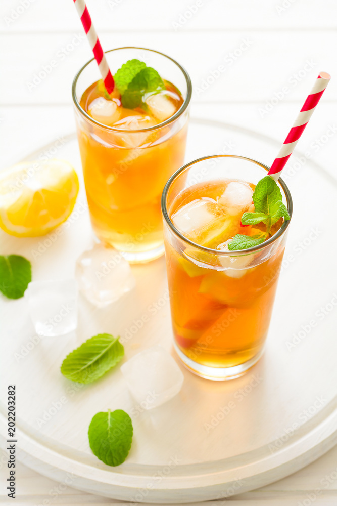 Glasses of iced tea with lemon slices and mint on white wooden background Glasses of iced tea with lemon slices and mint on white wooden background