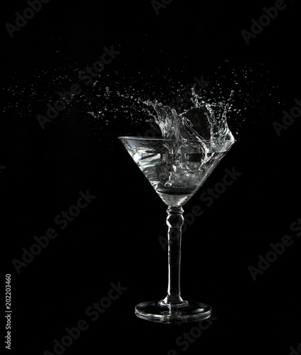 Martini glass low key photo in studio on black background and water plash