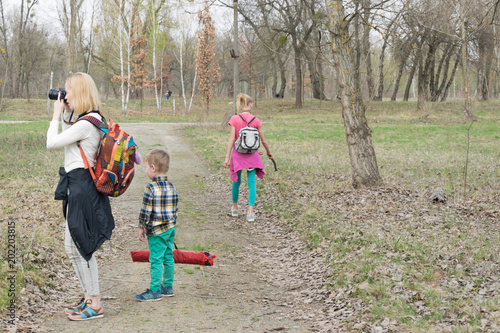 Mom and two children with a dog are walking in the park.