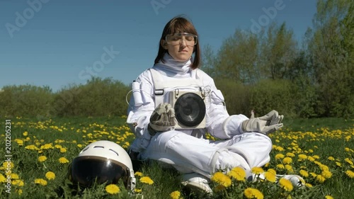 Girl cosmonaut practicing meditation on a flower field photo