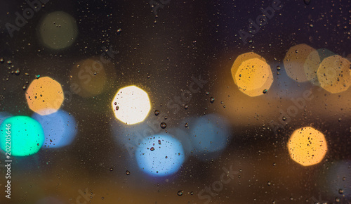 The background with the city lights at night with water drops on glass