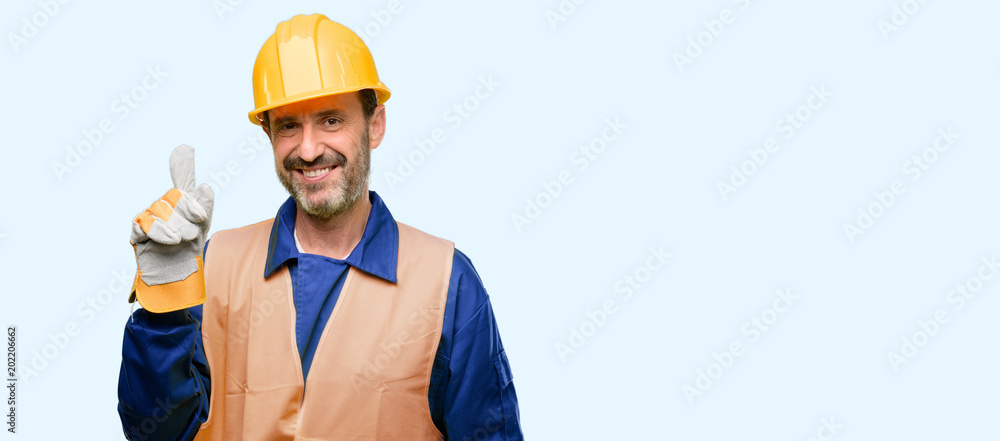 Senior engineer man, construction worker pointing away side with finger isolated over blue background Senior engineer man, construction worker pointing away side with finger isolated over blue background