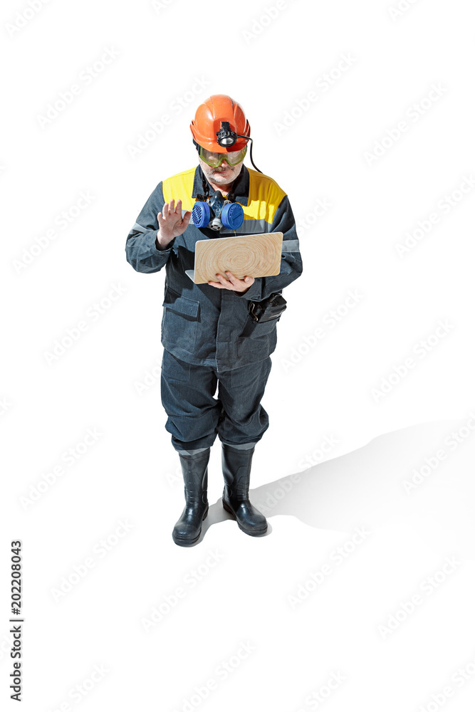 The studio shot of senior bearded male miner standing at the camera on a white background. The studio shot of senior bearded male miner standing at the camera on a white background.