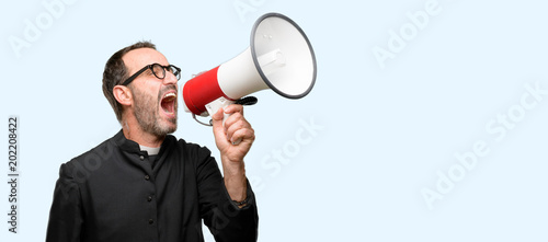 Priest religion man communicates shouting loud holding a megaphone, expressing success and positive concept, idea for marketing or sales isolated over blue background