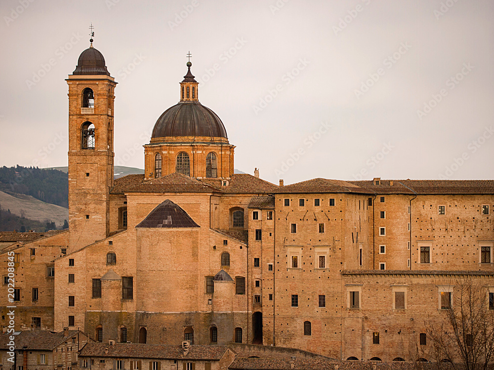 view at sunset of the beautiful and ancient city of Urbino, UNESCO World Heritage, with a dome and bell tower illuminated by the warm light of the spring sun.