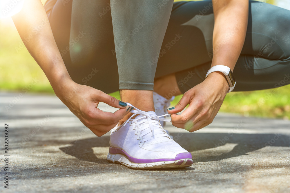 femal jogger ties her shoes femal jogger ties her shoes