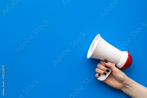 Attract attention concept. Megaphone in hand on blue background top view copy space