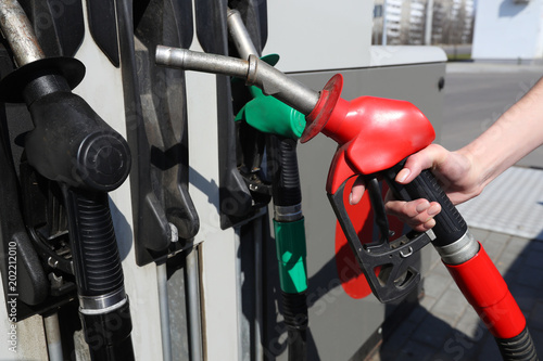Woman hold fuel nozzle to add fuel in car at gas station