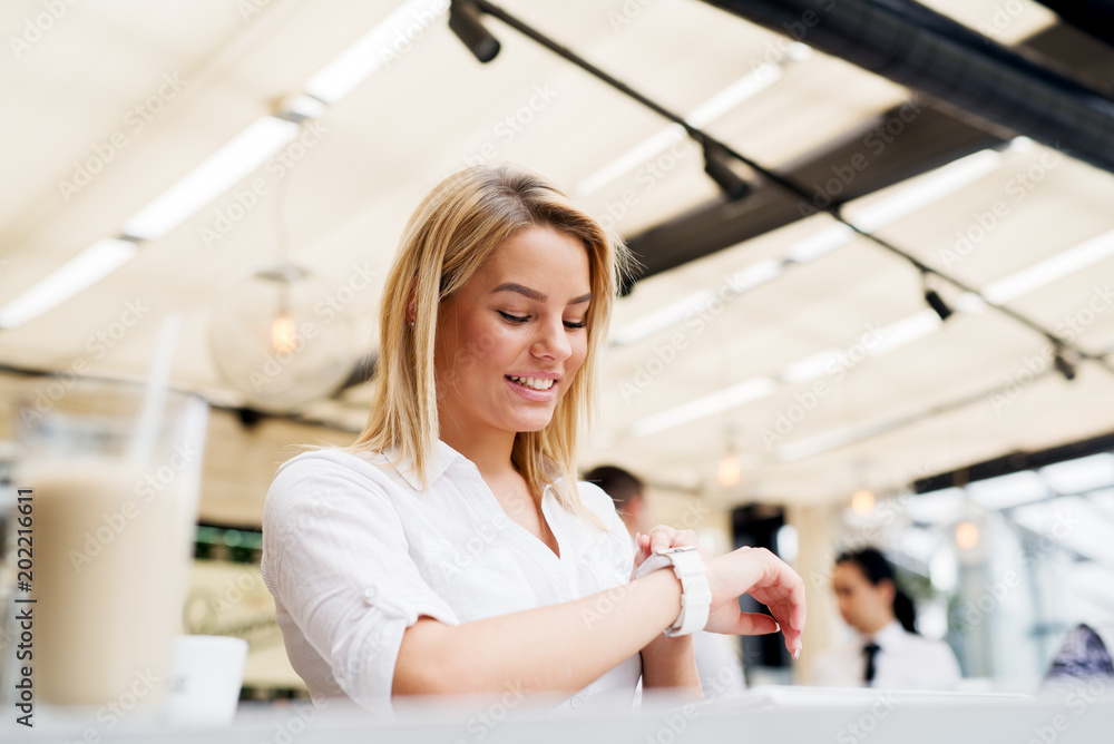 Beautiful stylish girl using the modern watch in a coffee shop. Beautiful stylish girl using the modern watch in a coffee shop.