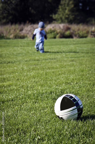 Little boy is playing football in the field