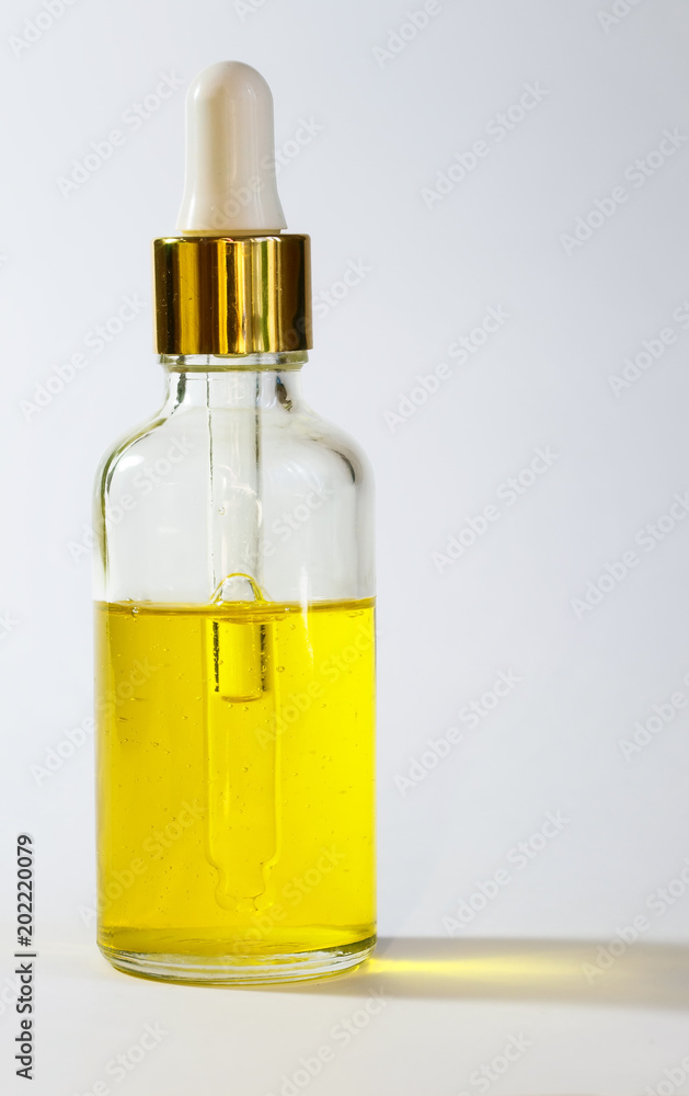 bright Golden cosmetic oil stands in clear vial with dropper on white background bright Golden cosmetic oil stands in clear vial with dropper on white background