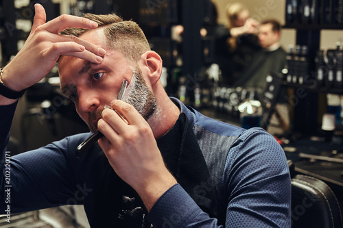 Tableau sur toile Portrait of a stylish male who himself shaving in a hairdressing salon