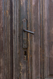 Vintage metal black and rusty door handle. Old wooden brown doors.