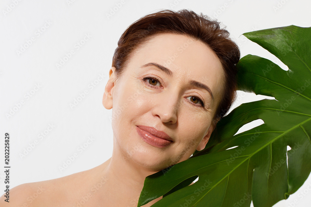 Spa and anti aging concept. Woman face with wrinkles and leaf isolated on white background. Summer holidays. Menopause. Copy space Spa and anti aging concept. Woman face with wrinkles and leaf isolated on white background. Summer holidays. Menopause. Copy space
