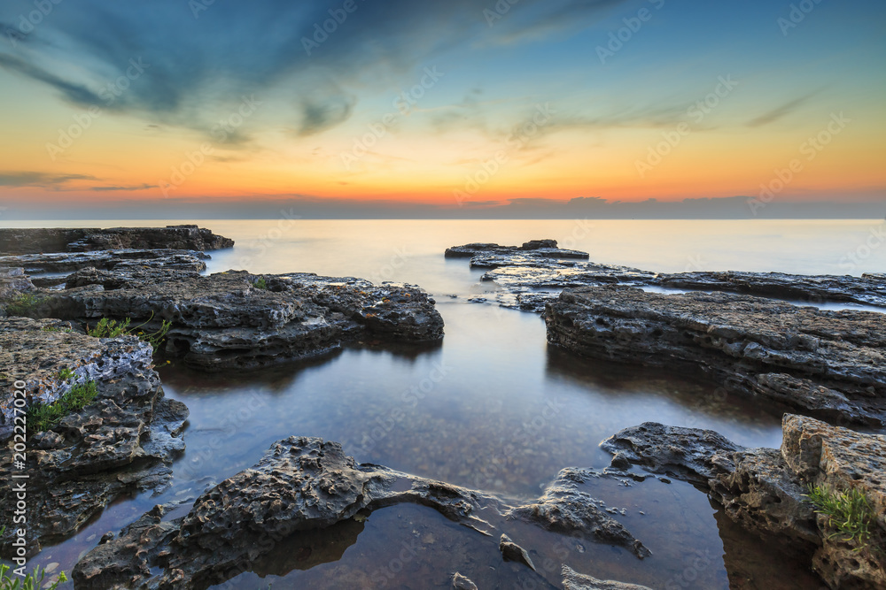 Enjoying the colorful sunset on a beach with rocks on the Adriatic Sea coast Istria Croatia