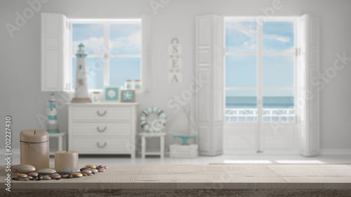 Wooden vintage table top or shelf with candles and pebbles  zen mood  over blurred mediterranean white living  windows with sea panorama  white architecture interior design