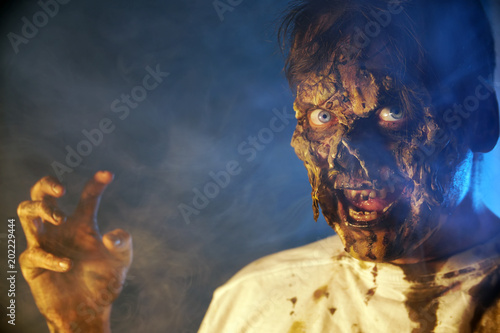 Fototapeta Naklejka Na Ścianę i Meble -  scary zombie closeup on dark background in Halloween makeup