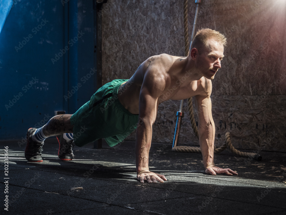 Obraz premium Handsome shirtless muscular young man exercising pecs in gym with push-ups