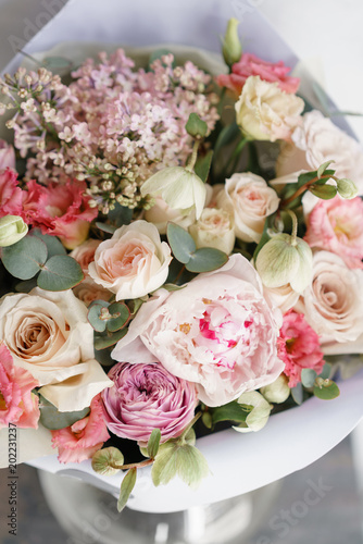 bouquet of beautiful flowers with peony on gray table. Floristry concept. Spring colors. the work of the florist at a flower shop. Vertical photo © malkovkosta