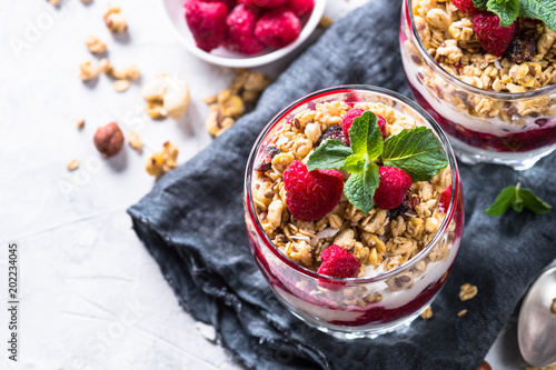 Layered dessert with yogurt, granola, jam and raspberries.