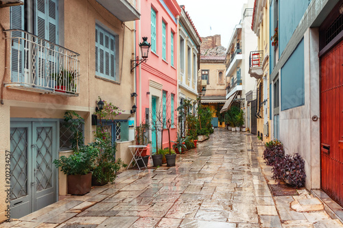 Beautiful cosy narrow street with stairs in famous Placa district in the rainy day, Old Town of Athens, Greece