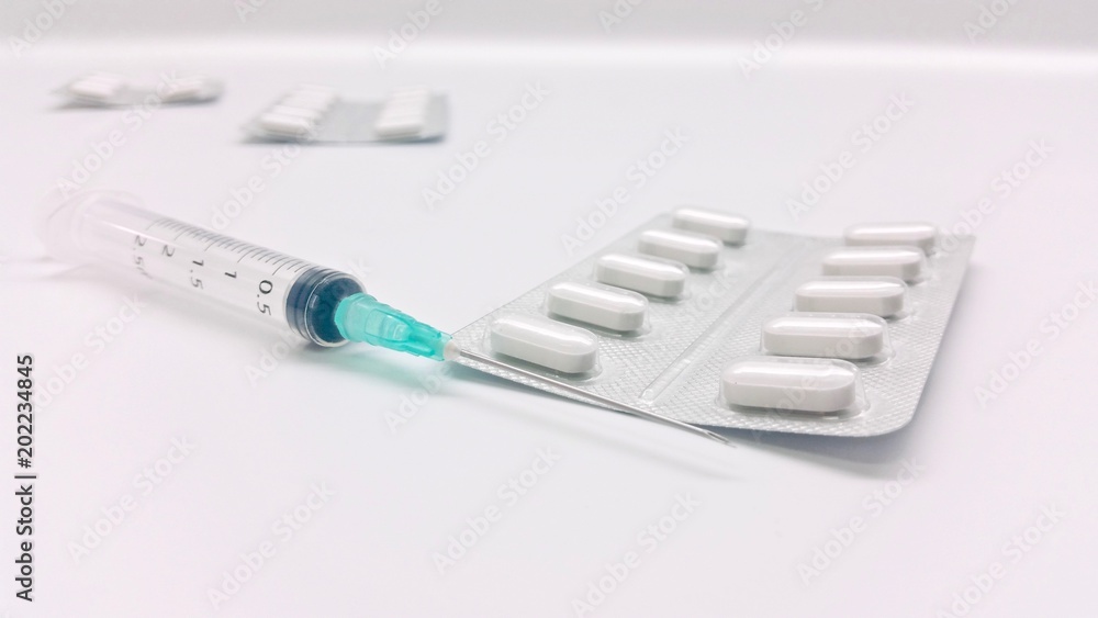 Disposable syringe and white tablets Disposable syringe and white tablets