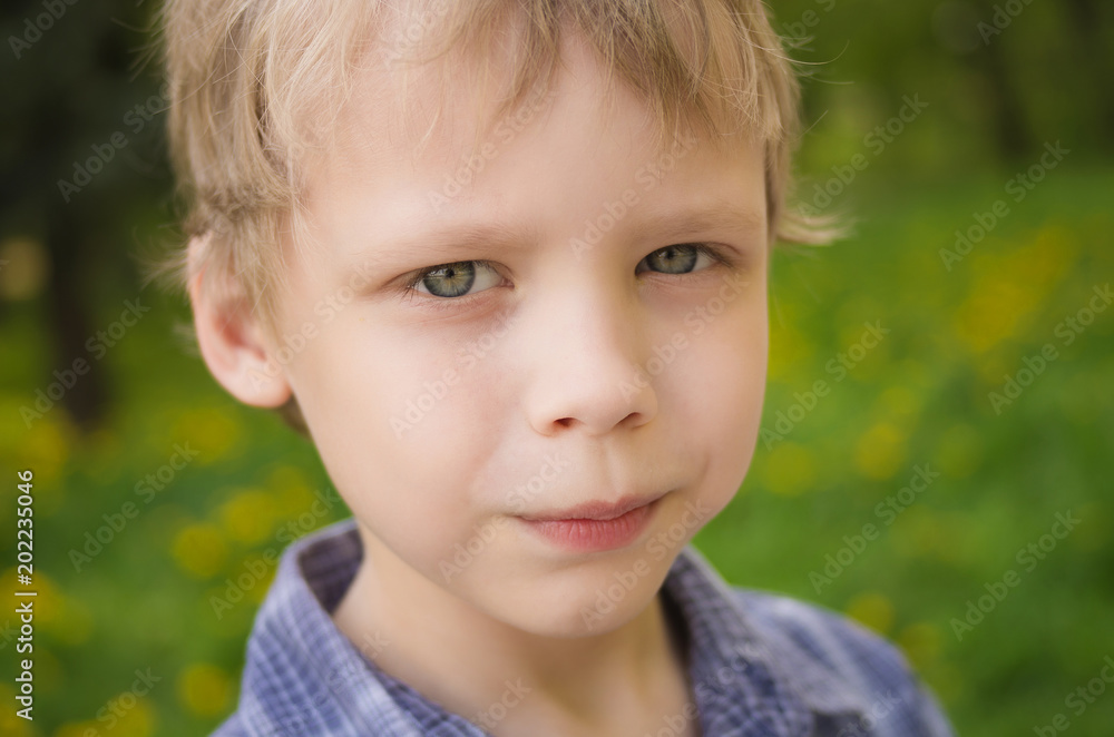 Closeup portrait of little cute funny boy with white hair looking at camera seriously while playing outdoors on warm spring or summer day. Horizontal color photography Closeup portrait of little cute funny boy with white hair looking at camera seriously while playing outdoors on warm spring or summer day. Horizontal color photography