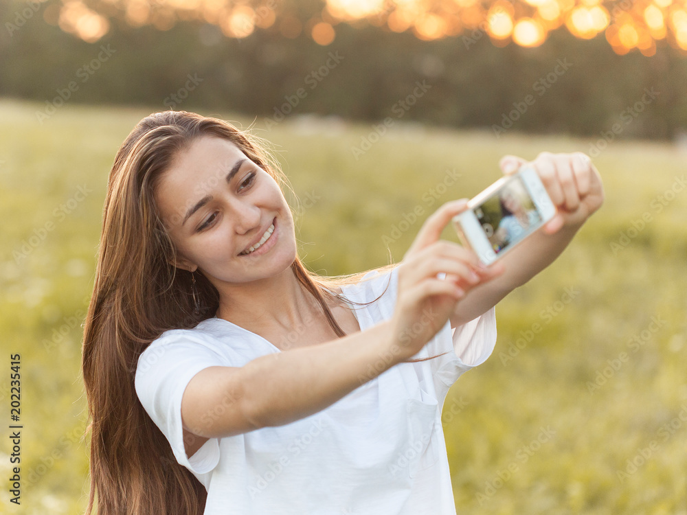 Young woman takes self portrait on mobile phone outdoors Young woman takes self portrait on mobile phone outdoors