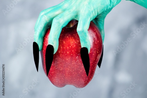 фотографія Beautiful red apple in green hands of old witch with black nails
