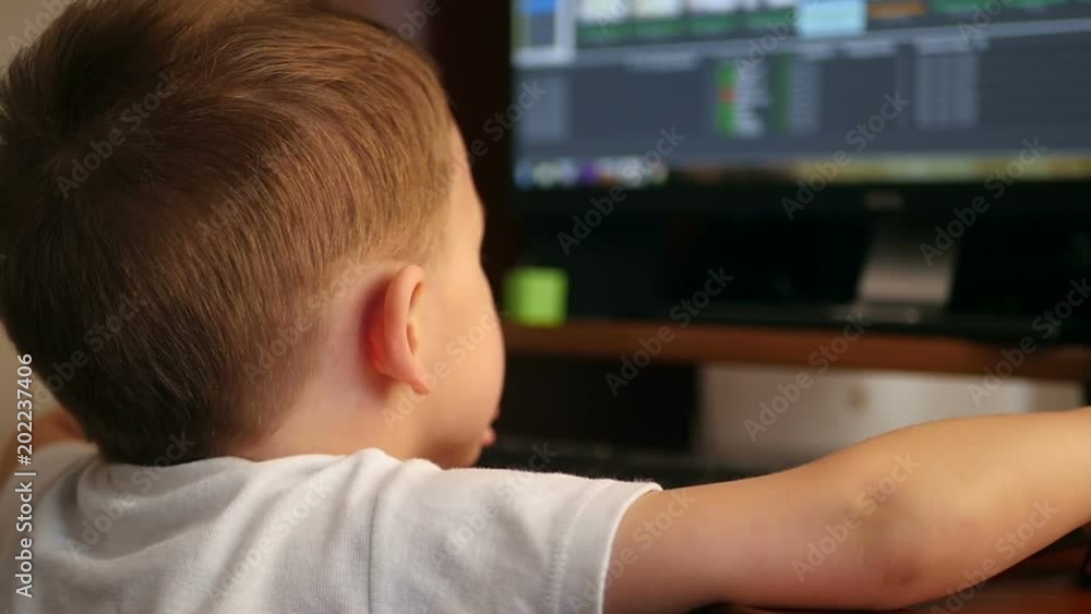 The child is sitting at the computer, playing games