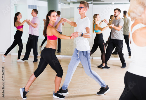 Dancing couples learning salsa at dance class