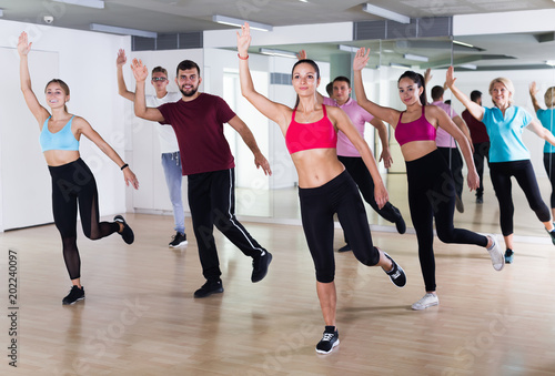 Group of active people training dance in studio