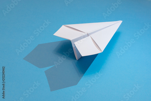 Foto white paper plane with shadow on a blue paper background