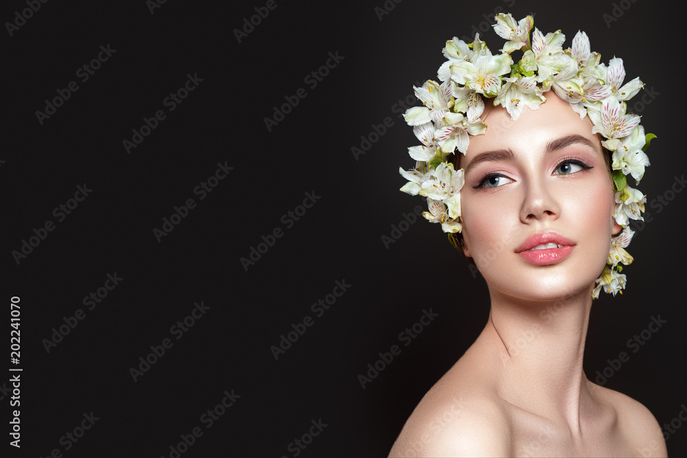 Beautiful woman portrait on black background with flowers on head.