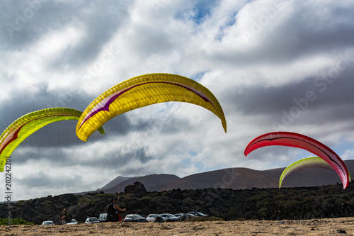 Paraplaners with paraplanes on sandy beach, extreme sport