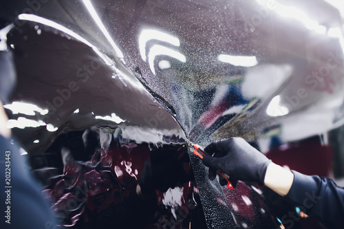 Applying tinting foil on car window in garage photo